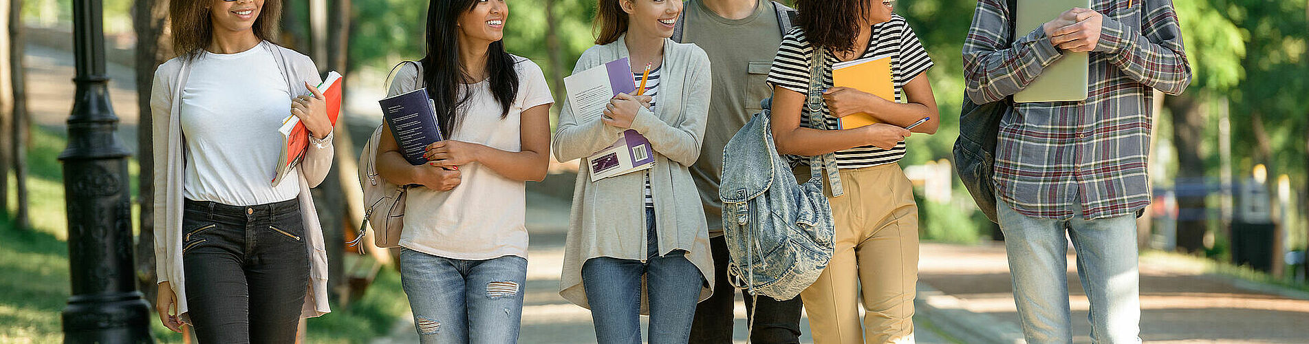 Multiethnic group of young cheerful students walking