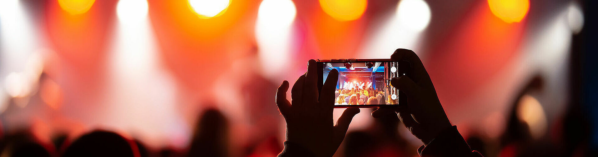 Person close up of recording video with smartphone during a concert.