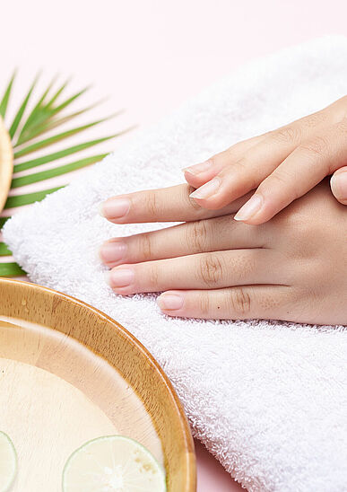 Woman soaking her hands in bowl of water and flowers, Spa treatm